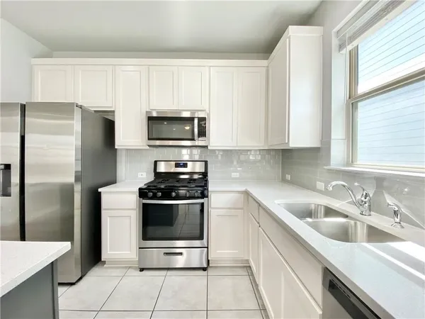 a kitchen with stainless steel appliances a stove a sink a refrigerator and a window
