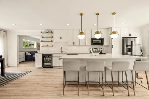 a kitchen with kitchen island granite countertop a table chairs sink and cabinets