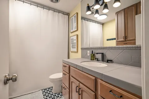 a bathroom with a granite countertop sink a toilet and a mirror
