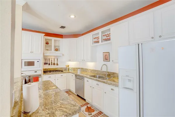 a kitchen with stainless steel appliances granite countertop a refrigerator sink and white cabinets