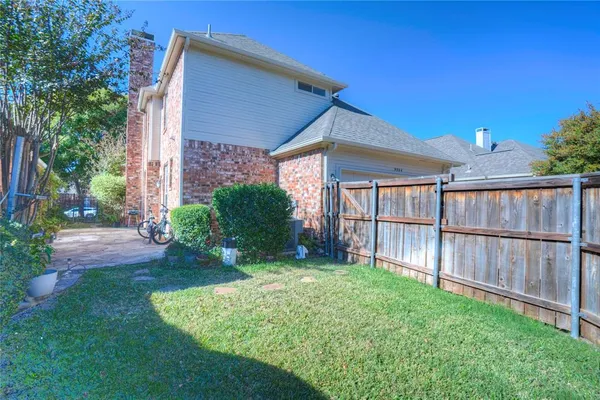 a view of a backyard with plants and large tree