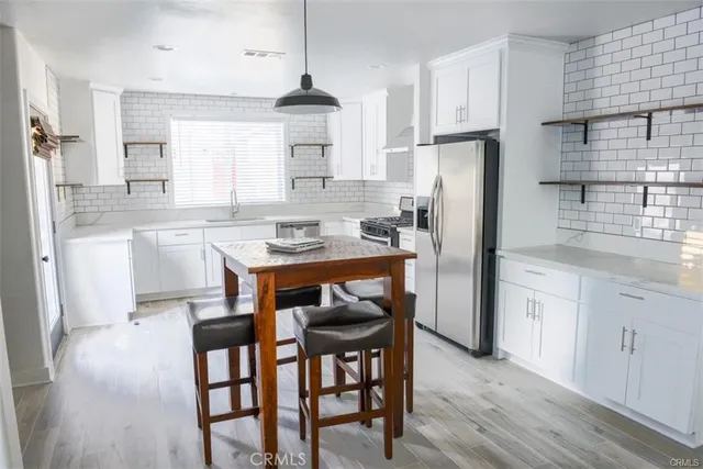 a kitchen with stainless steel appliances granite countertop a dining table chairs refrigerator and cabinets