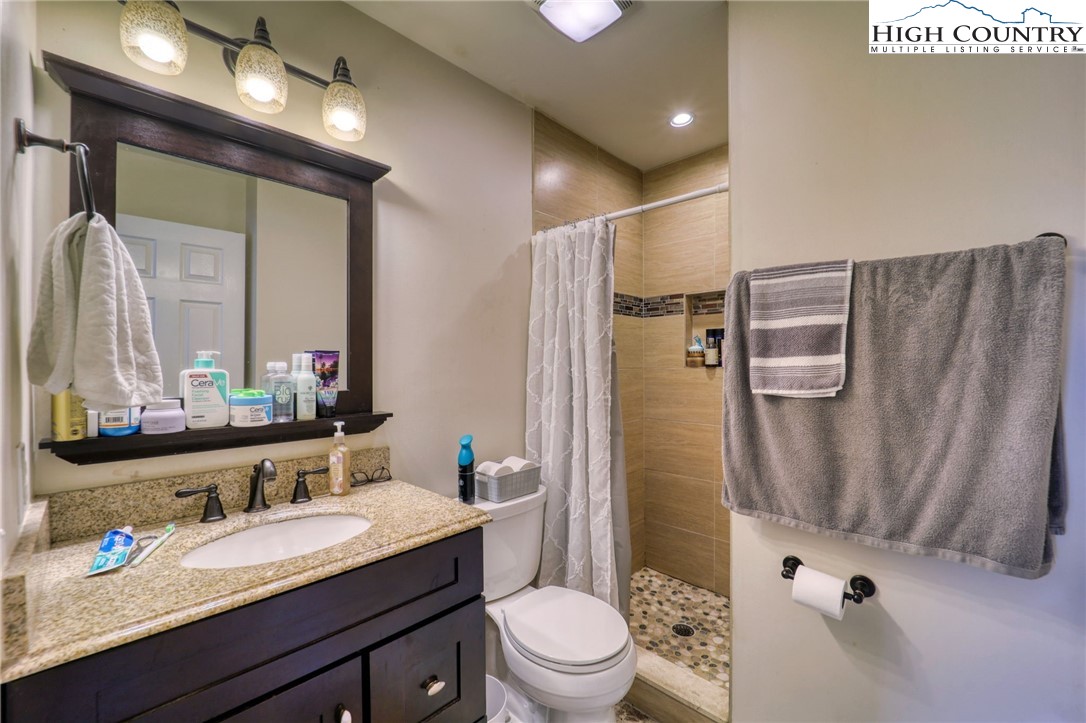 128 Zeb Street, Unit A304 Boone, NC 28607 - Photo 15 of 27 a bathroom with a granite countertop sink toilet a mirror a vanity and shower