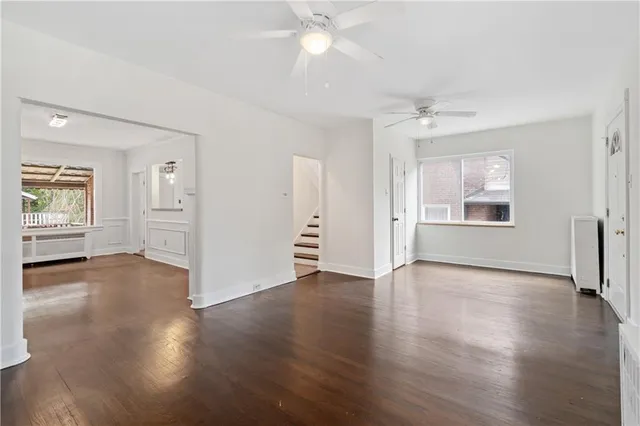 an empty room with wooden floor cabinet and windows