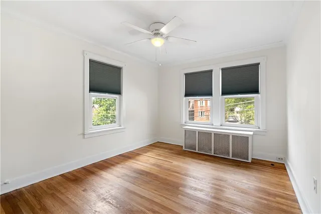 an empty room with wooden floor cabinet and windows