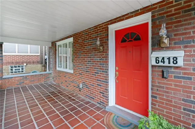 a front view of a building with a red door and a potted plant