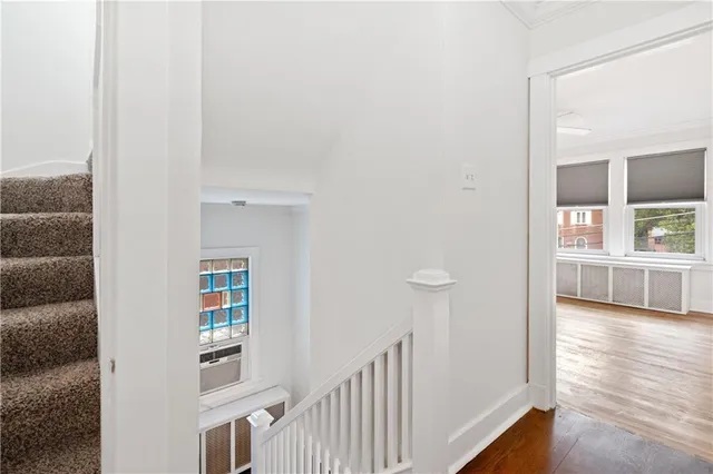 a view of a hallway with wooden floor and a living room