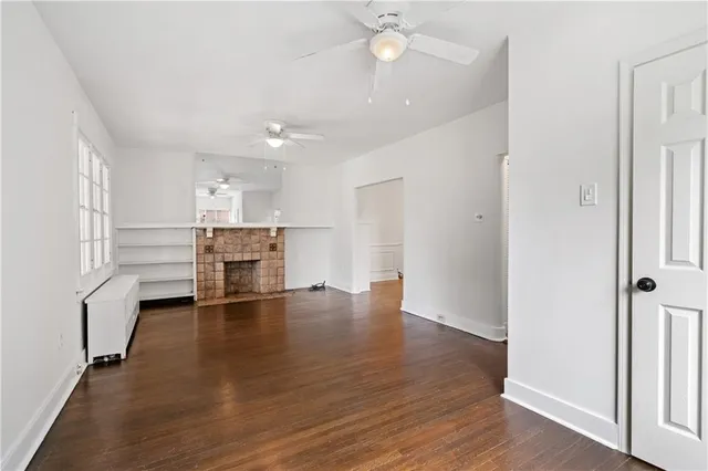 an empty room with wooden floor and kitchen view