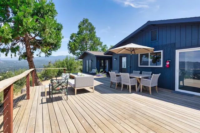 a view of a roof deck with table and chairs under an umbrella with wooden floor and fence