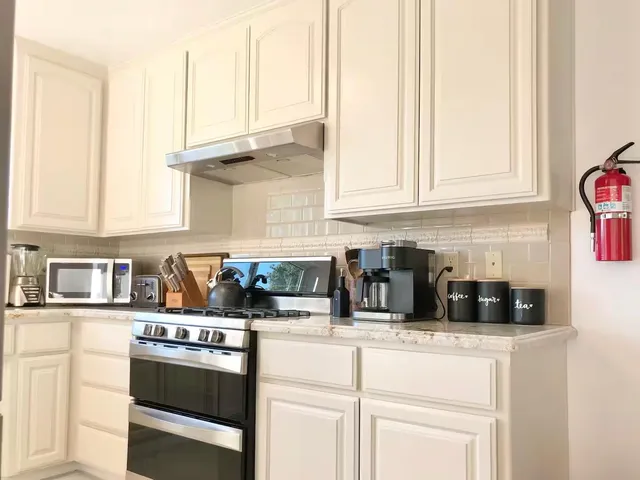 a kitchen with stainless steel appliances granite countertop a sink a stove and a white cabinets