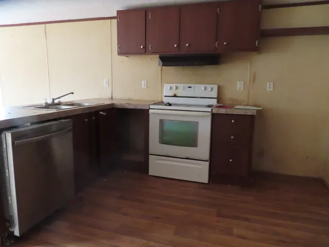 a kitchen with stainless steel appliances wooden cabinets and a wooden floor