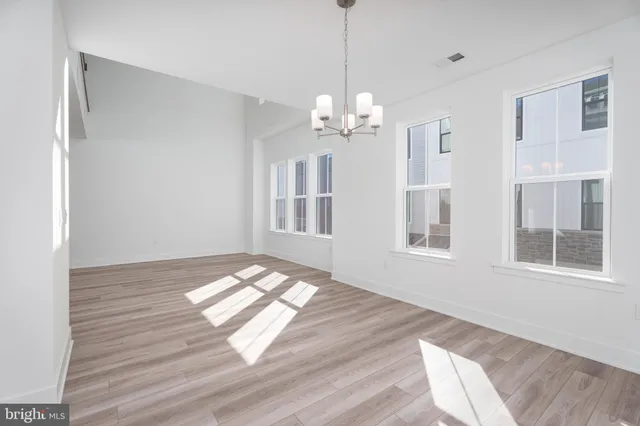 a view of an empty room with wooden floor and windows