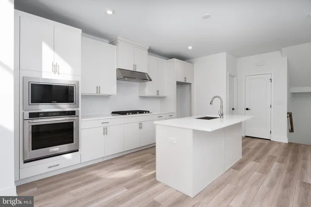 a kitchen with stainless steel appliances white cabinets a sink and a stove