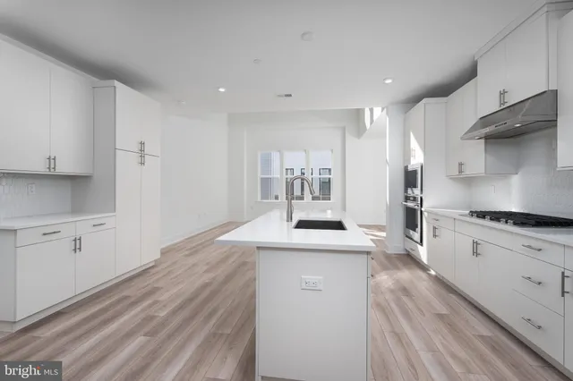 a kitchen with stainless steel appliances white cabinets a sink stove and refrigerator