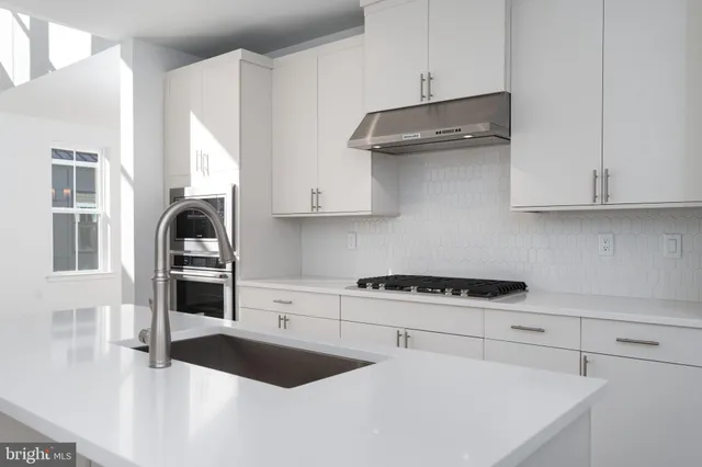 a kitchen with stainless steel appliances granite countertop a refrigerator stove and white cabinets