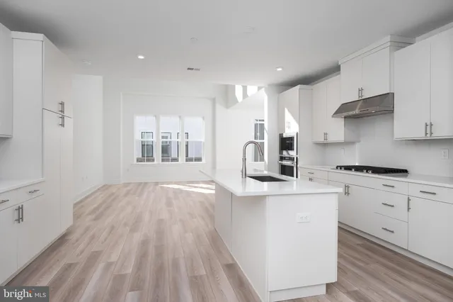 a kitchen with stainless steel appliances granite countertop a stove a sink and white cabinets with wooden floor