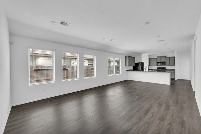 a view of empty room with kitchen and window