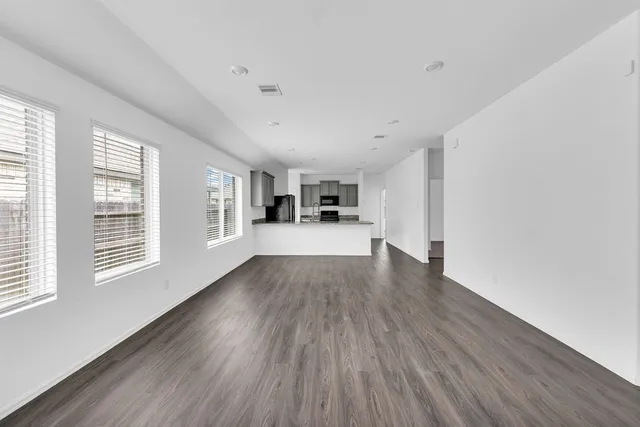 a view of a big room with wooden floor and windows