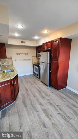 a kitchen with stainless steel appliances granite countertop a refrigerator a stove and a sink
