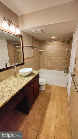 a bathroom with a granite countertop sink a toilet and bathtub