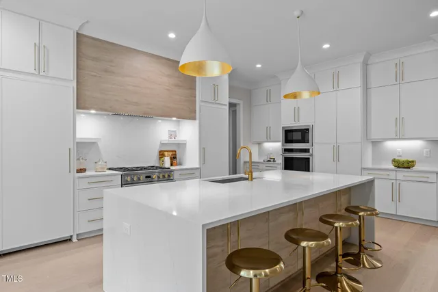 a kitchen with kitchen island a large counter top space a sink stainless steel appliances and cabinets