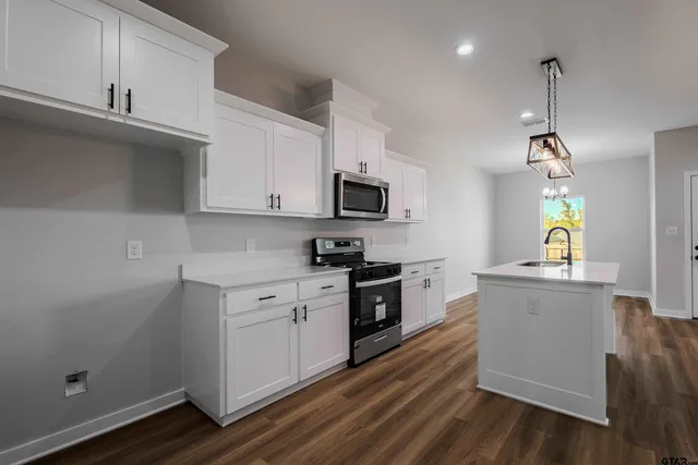 a kitchen with granite countertop a stove top oven a sink dishwasher and a refrigerator