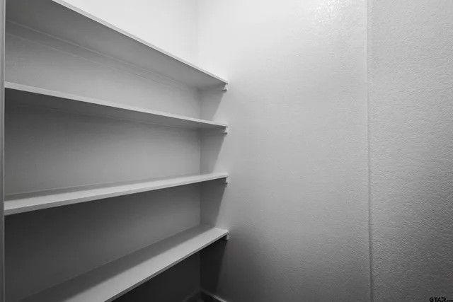 a view of an empty room with window and chandelier fan