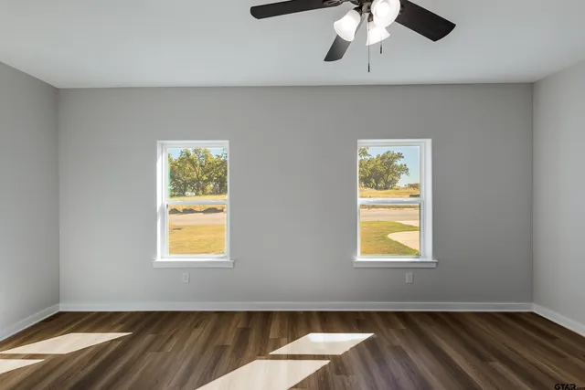 a view of empty room with wooden floor and fan