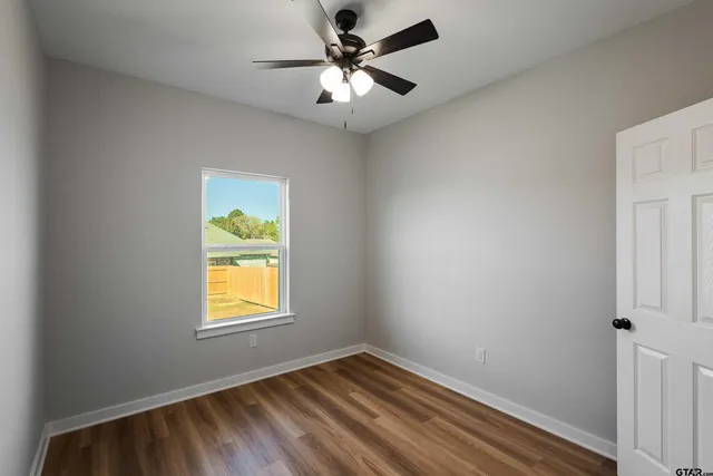 a view of empty room with wooden floor and fan