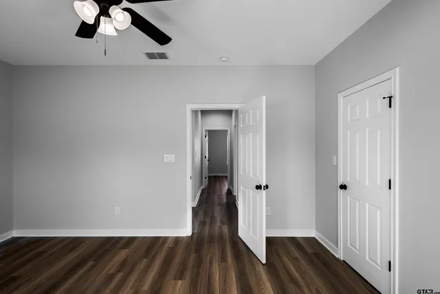 a view of a hallway with wooden floor and a bathroom