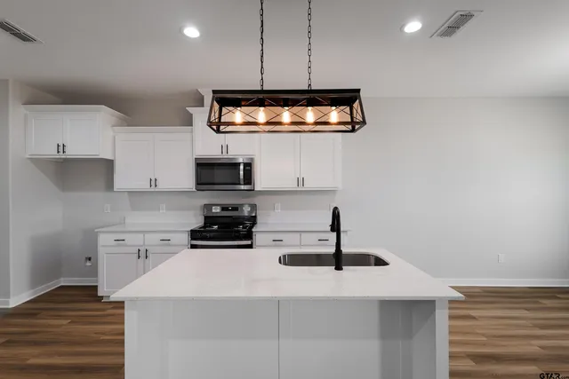 a kitchen with stainless steel appliances a stove a sink and white cabinets