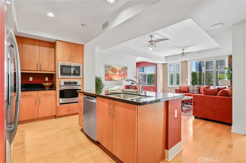 150 The Promenade North, Unit 202 Long Beach, CA 90802 - Photo 7 of 59 a kitchen with stainless steel appliances granite countertop a stove top oven a sink dishwasher a dining table and chairs with wooden floor