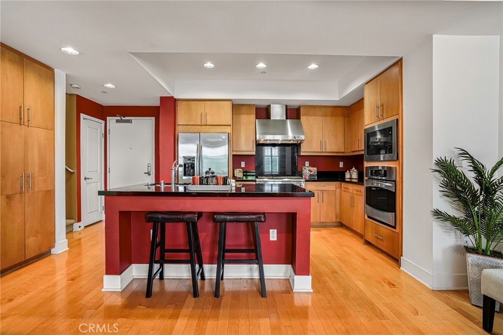150 The Promenade North, Unit 202 Long Beach, CA 90802 - Photo 8 of 59 a kitchen with stainless steel appliances granite countertop a stove a sink a refrigerator and a dining table with wooden floor