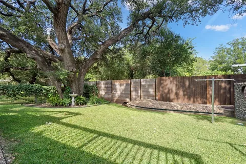 a view of a backyard with wooden fence and a large tree