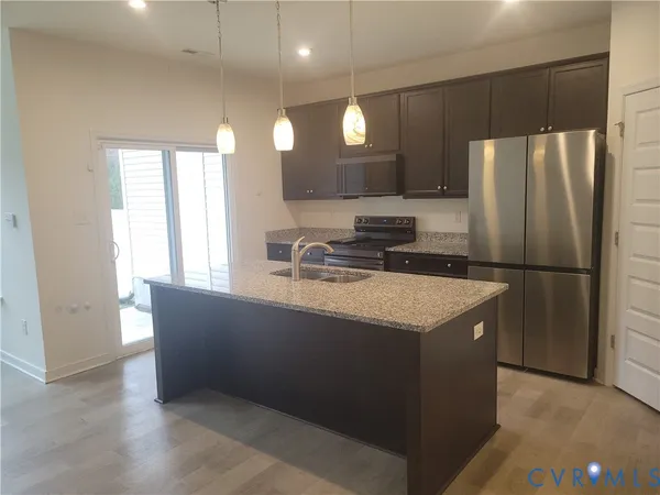 a kitchen with granite countertop a refrigerator a sink and wooden cabinets