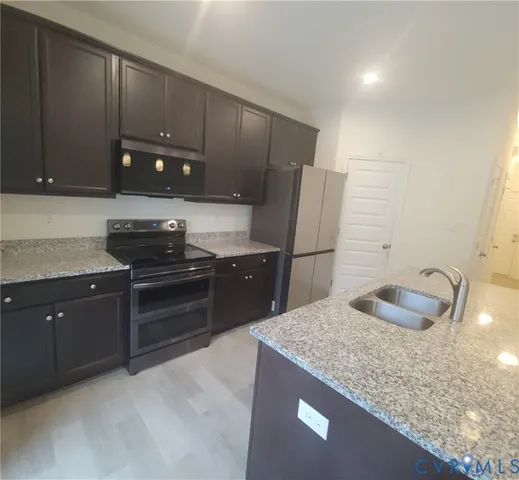 a kitchen with stainless steel appliances granite countertop a sink and a refrigerator