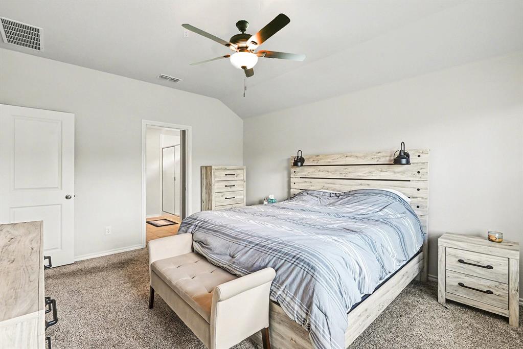 513 Bronze Circle West Springtown, TX 76082 - Photo 15 of 25 Carpeted bedroom featuring a vaulted ceiling with a ceiling fan, white paneled door, and built-in wall sconces flanking the bed