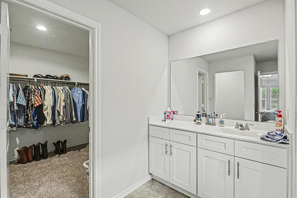 513 Bronze Circle West Springtown, TX 76082 - Photo 17 of 25 Bathroom vanity featuring a dual sink, white cabinetry with silver hardware, and a large wall-mounted mirror