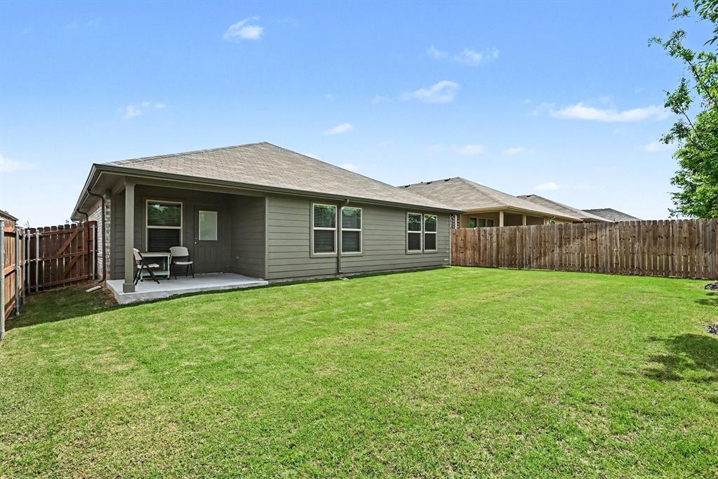 513 Bronze Circle West Springtown, TX 76082 - Photo 24 of 25 Expansive backyard featuring a large green lawn, full wood privacy fencing, and a covered concrete patio