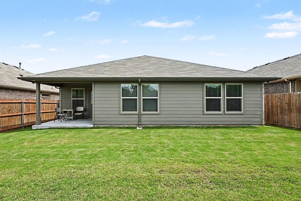 513 Bronze Circle West Springtown, TX 76082 - Photo 25 of 25 Expansive grassy backyard featuring a covered patio, gray horizontal siding, multiple windows, and wood privacy fencing