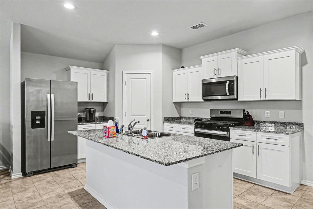 513 Bronze Circle West Springtown, TX 76082 - Photo 8 of 25 Kitchen featuring white cabinetry, granite countertops, an island with an undermount sink, stainless steel appliances, and recessed lighting
