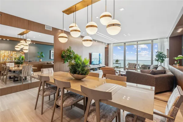 a living room with couches a large dining table and large window with wooden floor