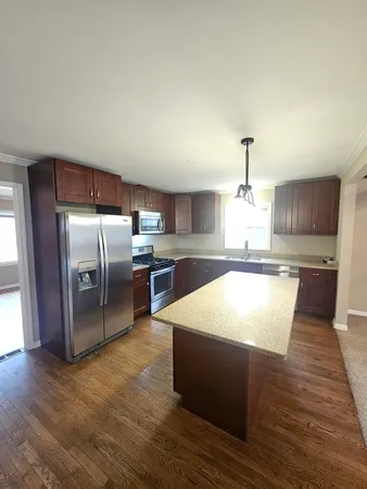 a large kitchen with stainless steel appliances kitchen island granite countertop a large counter top a sink a stove and a refrigerator