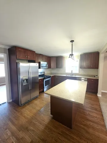 a large kitchen with kitchen island a stove a chimney wooden cabinets and a dining table