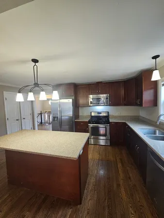 a large kitchen with kitchen island a stove a chimney wooden cabinets and a dining table