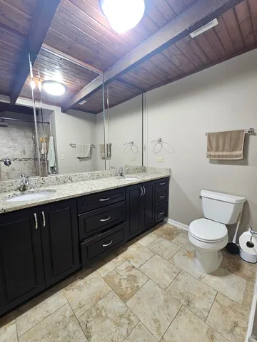 a spacious bathroom with a granite countertop sink a toilet and a mirror