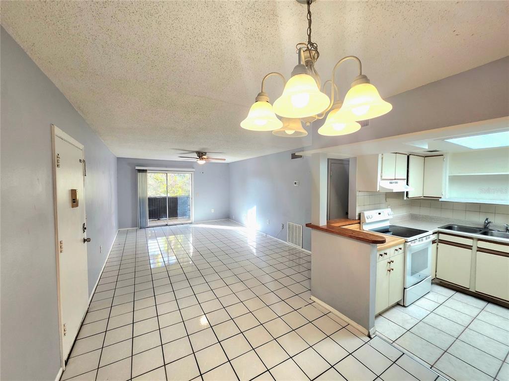 914 Lake Destiny Road, Unit G Altamonte Springs, FL 32714 - Photo 5 of 30 a kitchen with stainless steel appliances granite countertop a stove a sink dishwasher and white cabinets with wooden floor