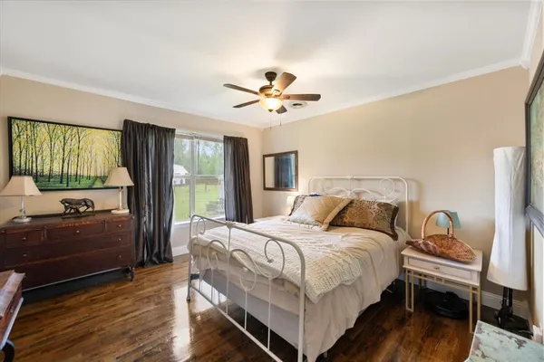 a bedroom with a bed and a dresser with wooden floor