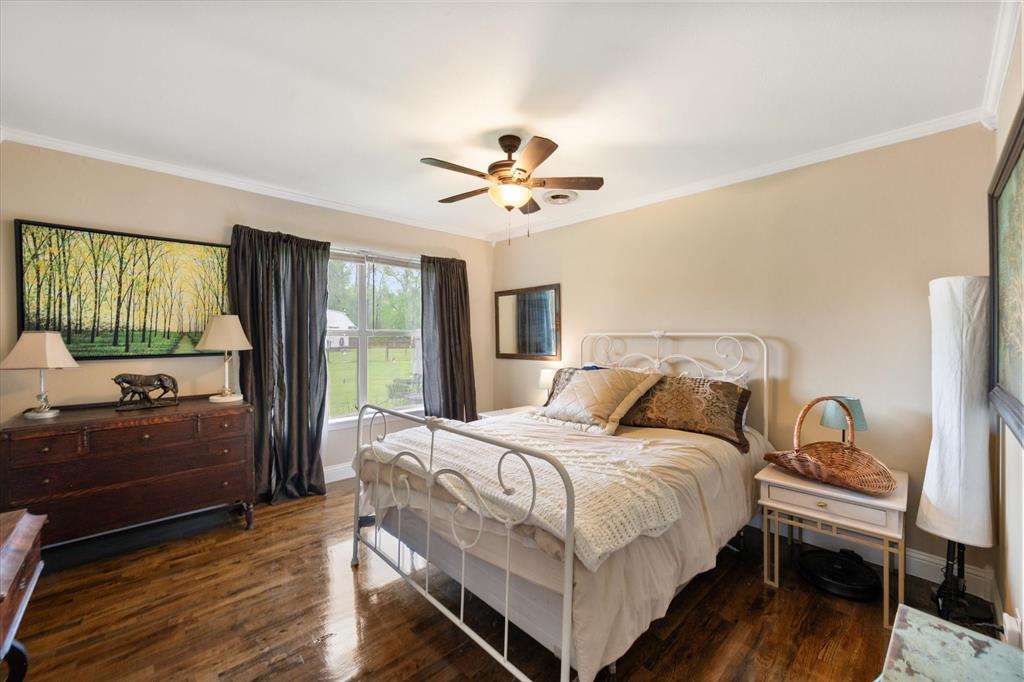 14036 Old Texaco Road Conroe, TX 77302 - Photo 14 of 40 a bedroom with a bed and a dresser with wooden floor