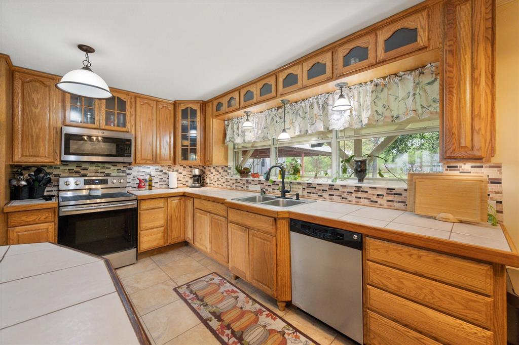 14036 Old Texaco Road Conroe, TX 77302 - Photo 7 of 40 a kitchen with stainless steel appliances kitchen island granite countertop a sink and cabinets